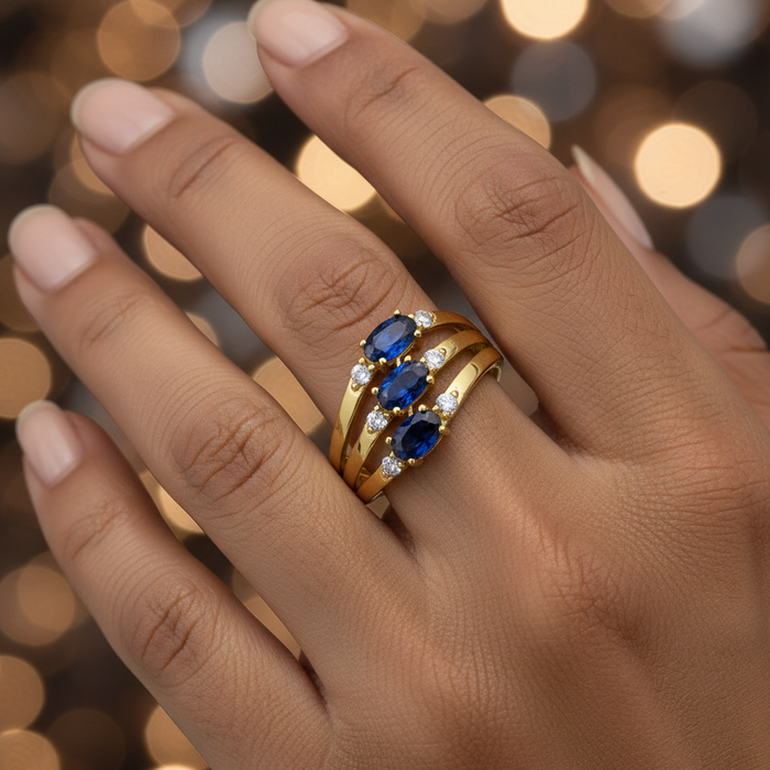 Gold ring with blue gemstones on a blurred background