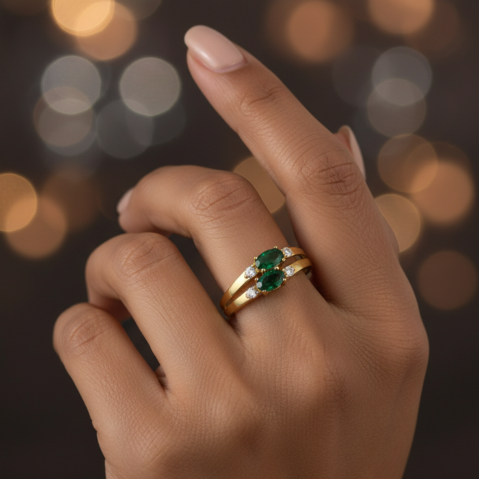 Gold ring with a green gemstone on a blurred lights background