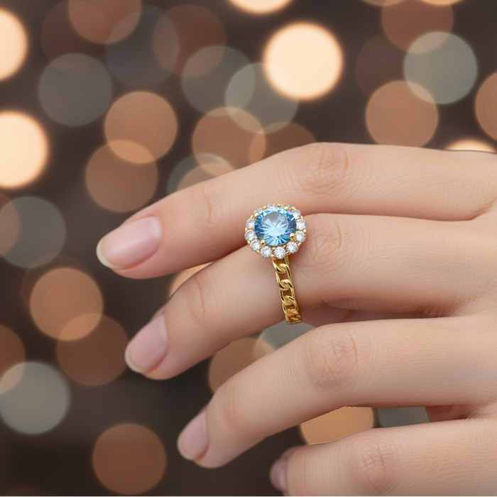 Gold ring with a blue gemstone on a blurred bokeh background
