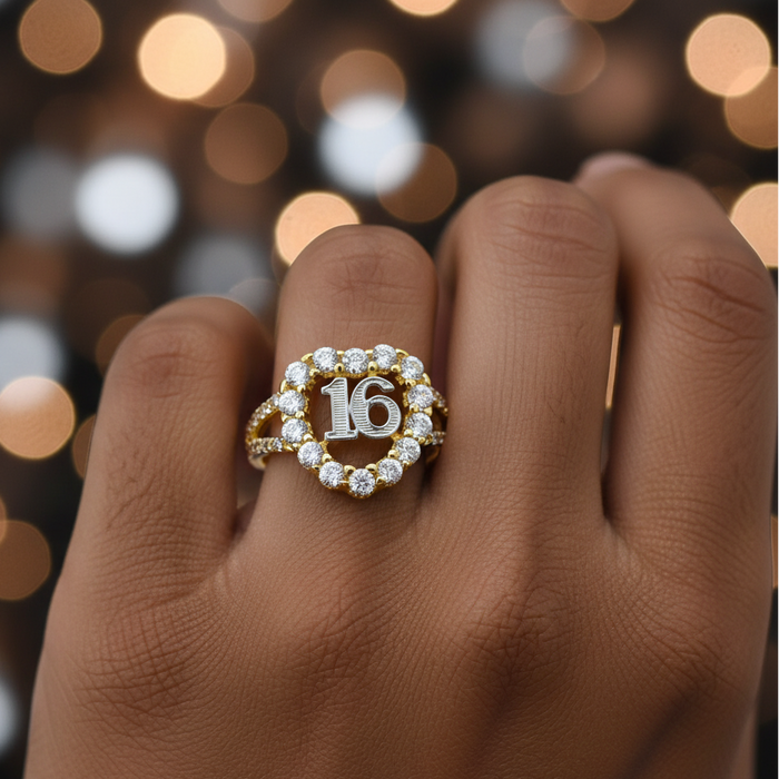 Gold ring with number 16 on a person's finger against a blurred bokeh background