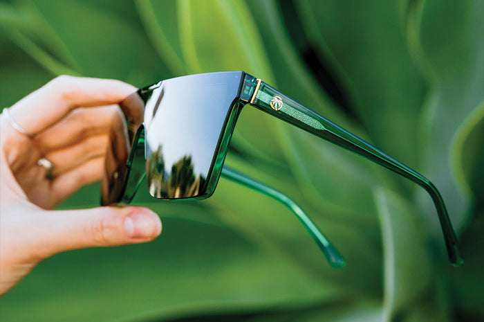 Hand holding the Clarity Sunglasses: Cycad Green
