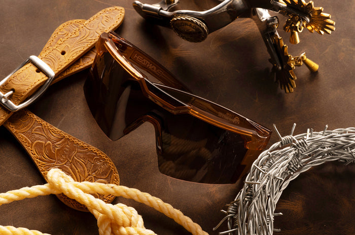The Future Tech Sunglasses: Saddle Z87+ on a wood table next to cowboy accessories