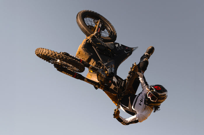 Man wearing The MXG-250 Moto Goggle - Saddle doing a trick in the air on dirtbike