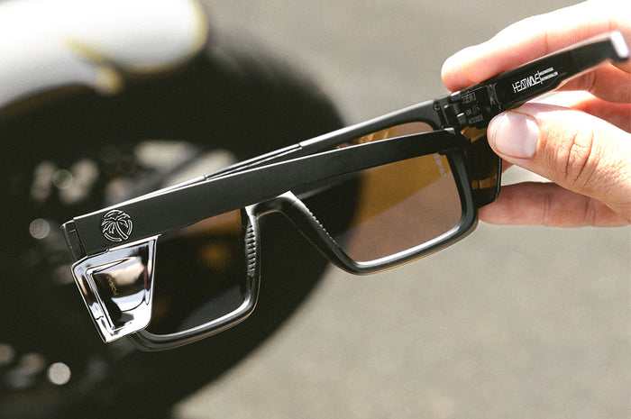 Hand holding the Heat Wave Visual Performance Quatro Sunglasses with black frame, silver lens and matching colored side shields.