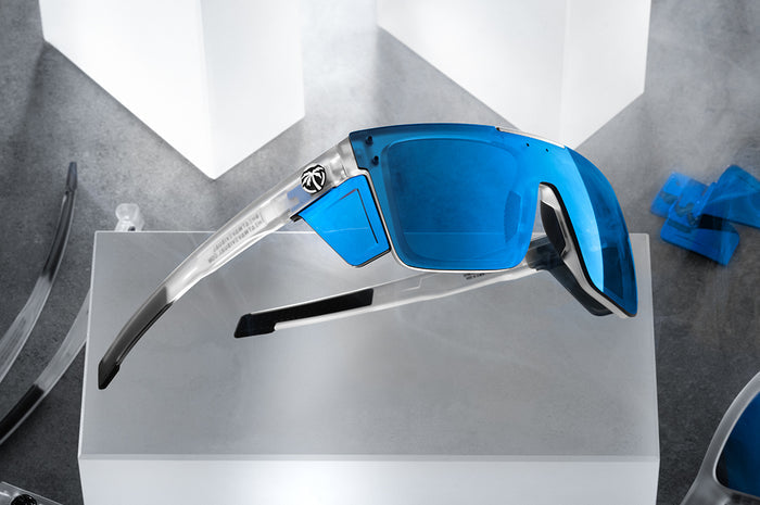 Indoor studio shot of the Performance Quatro Sunglasses: Vapor Frost Frame Coastal Lens Z87+ with blue side shields on a concrete block.