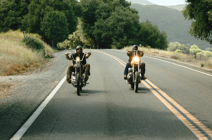 Two men on motorcycles driving on a road wearing Heat Wave Easy Rider Photocromic Sunglasses