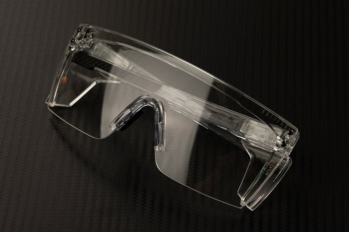 Laying on a table is the Heat Wave Visual Perforamance XL Lazer Face Sunglasses with clear frame, anti-fog clear lens and clear side shields.