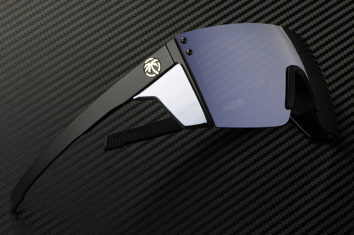 Laying on a table is the Heat Wave Visual Performance Lazer Face Sunglasses with black frame, silver lens and matching colored side shields.