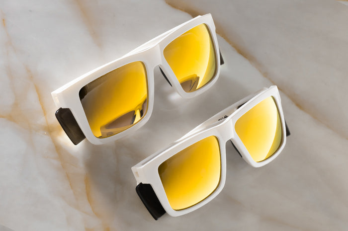 Two pairs of the Performance XL VISE Sunglasses: GLOSS WHITE Gold Lens Z87+ on a counter