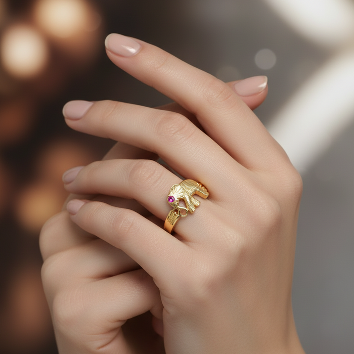 Gold ring with a bear design on a person's finger against a blurred background