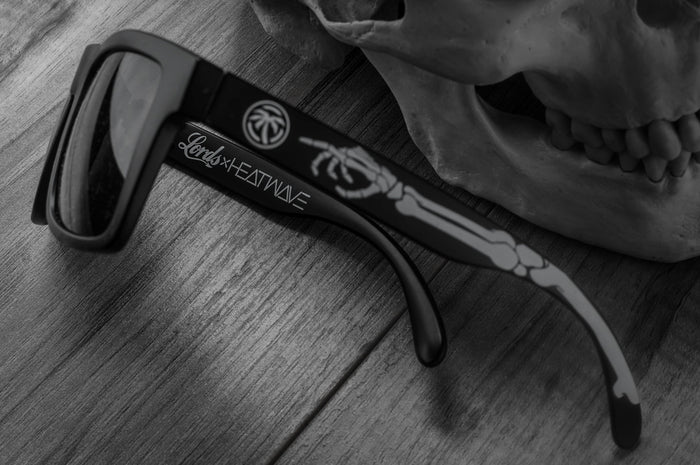 Close up side view of Heat Wave Visual Vise Sunglasses with black frame, bones print arms and black lenses.